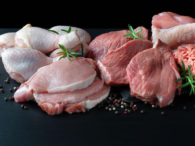 Chicken quarters, pork chops, and ground pork arranged with fresh rosemary.