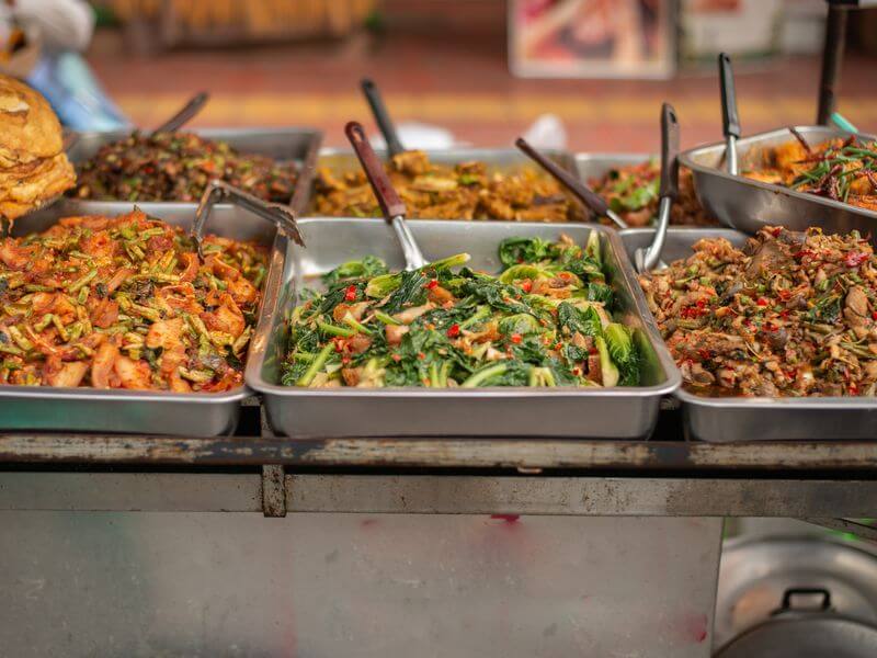 Trays of freshly made vegetable sides on a serving line.